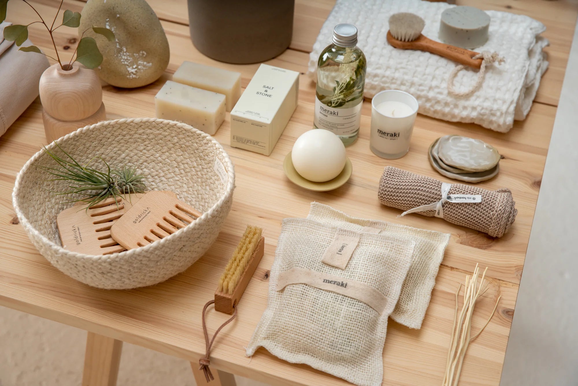 Bath and body goods including combs, candles, body soap, and Meraki products on the wooden surface of a table in the Seattle shop, Woodland Mod.