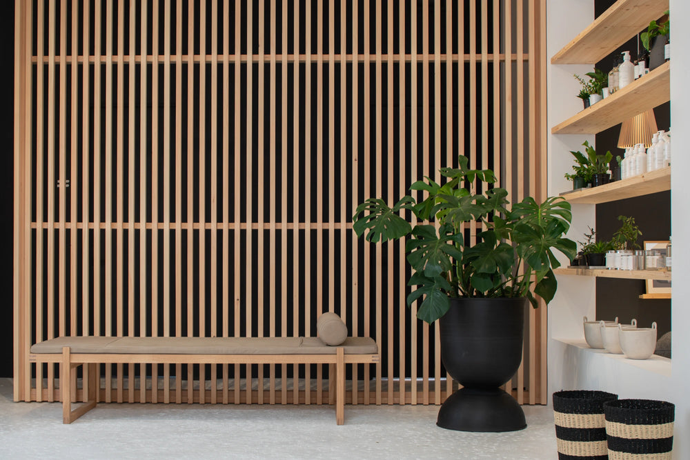 Scandinavian wooden sliding door in the store Woodland Mod behind a large black plant pot and Kristina Dam day bed.