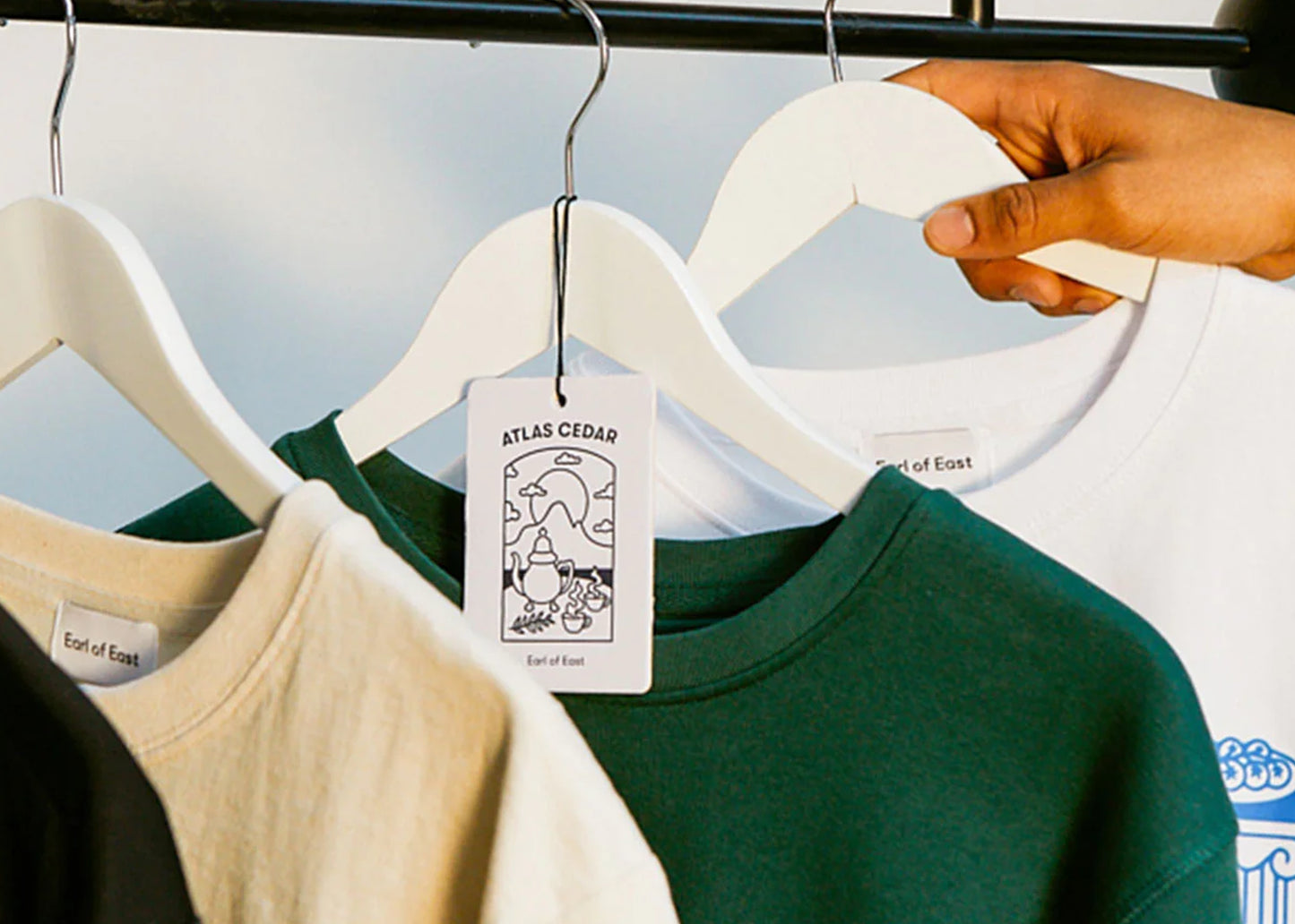 Atlas Cedar air freshener by Earl of East hanging from a clothing hook in a closet