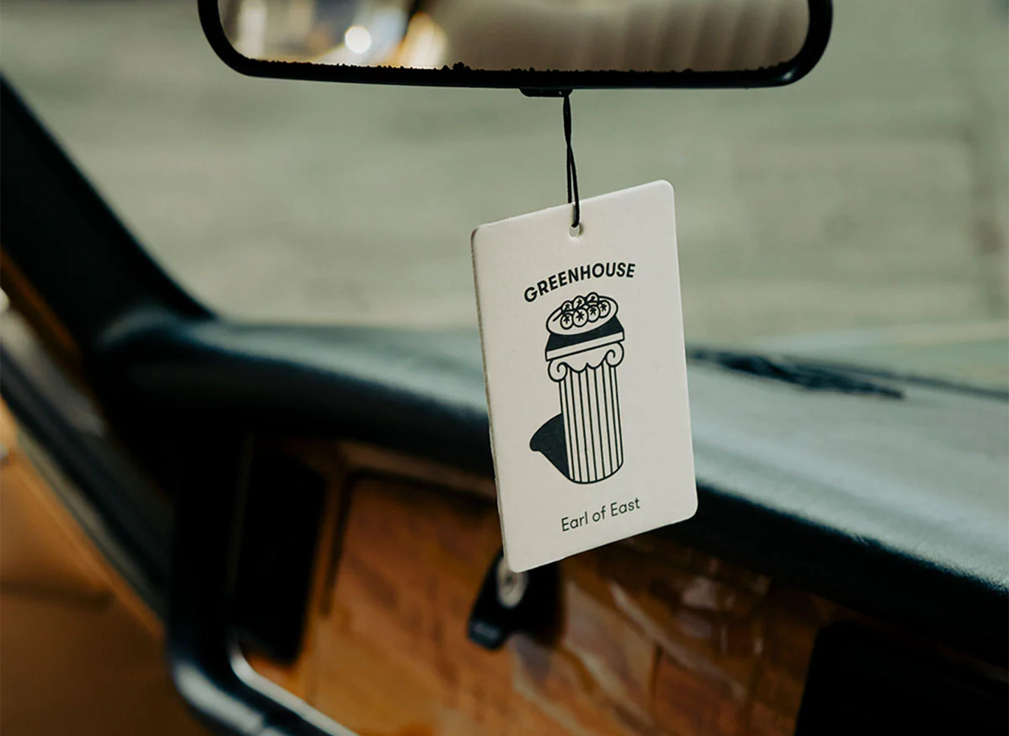 The Greenhouse air freshener by Earl of East hanging inside of a car window.