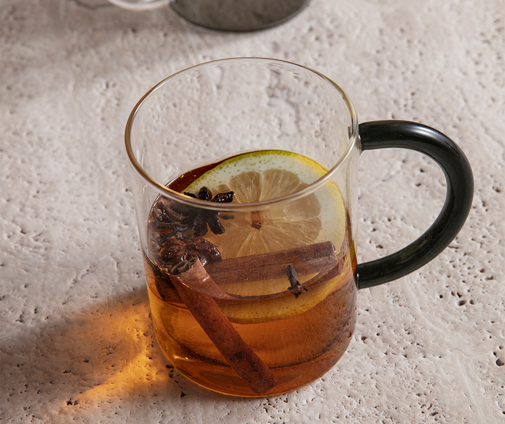 A clear still mug with dark glass handle by Ferm Living holding iced tea