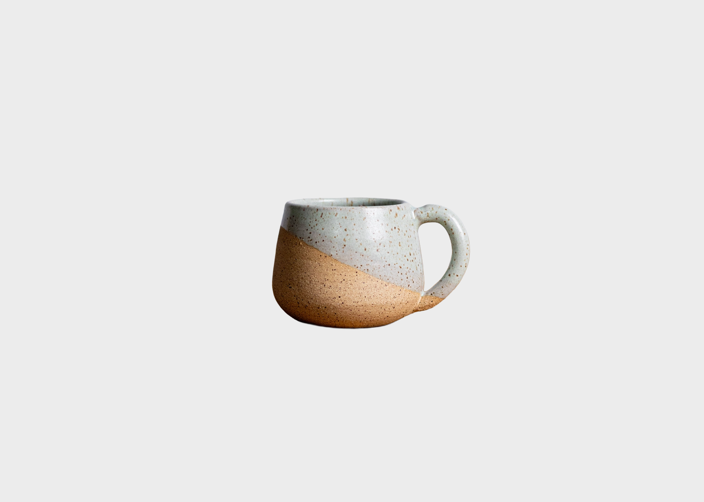 
                  
                    Light Blue Speckled ceramic mug set against a grey background
                  
                