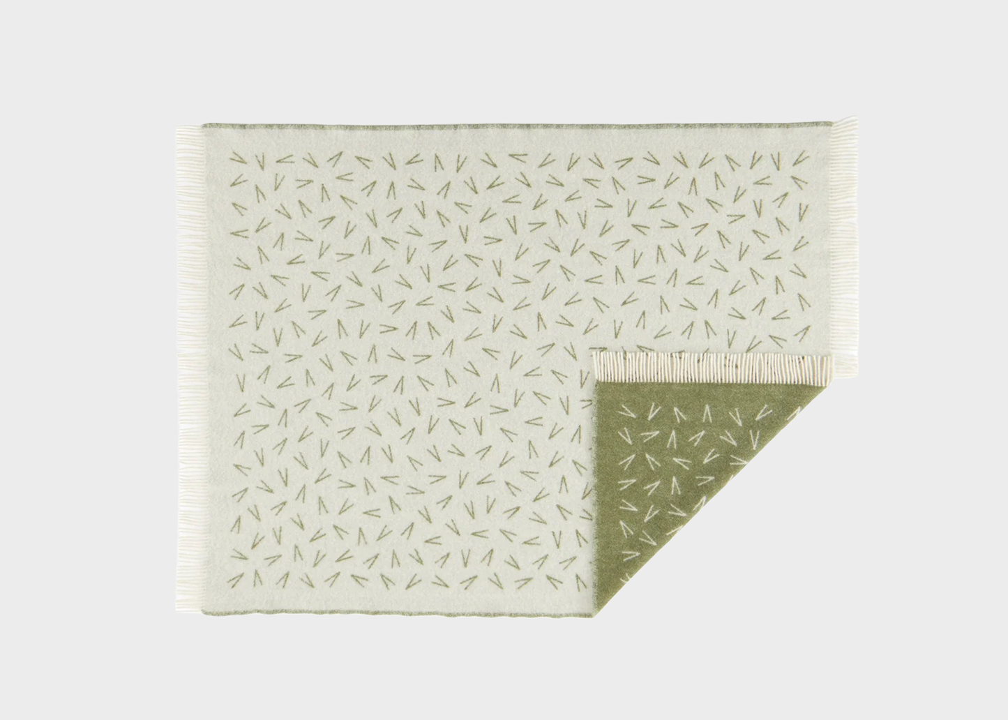 
                  
                    A rectangular woven throw blanket with a light cream background and a repeating pine needle pattern, featuring fringe on one side and a folded corner showing the reverse side.
                  
                