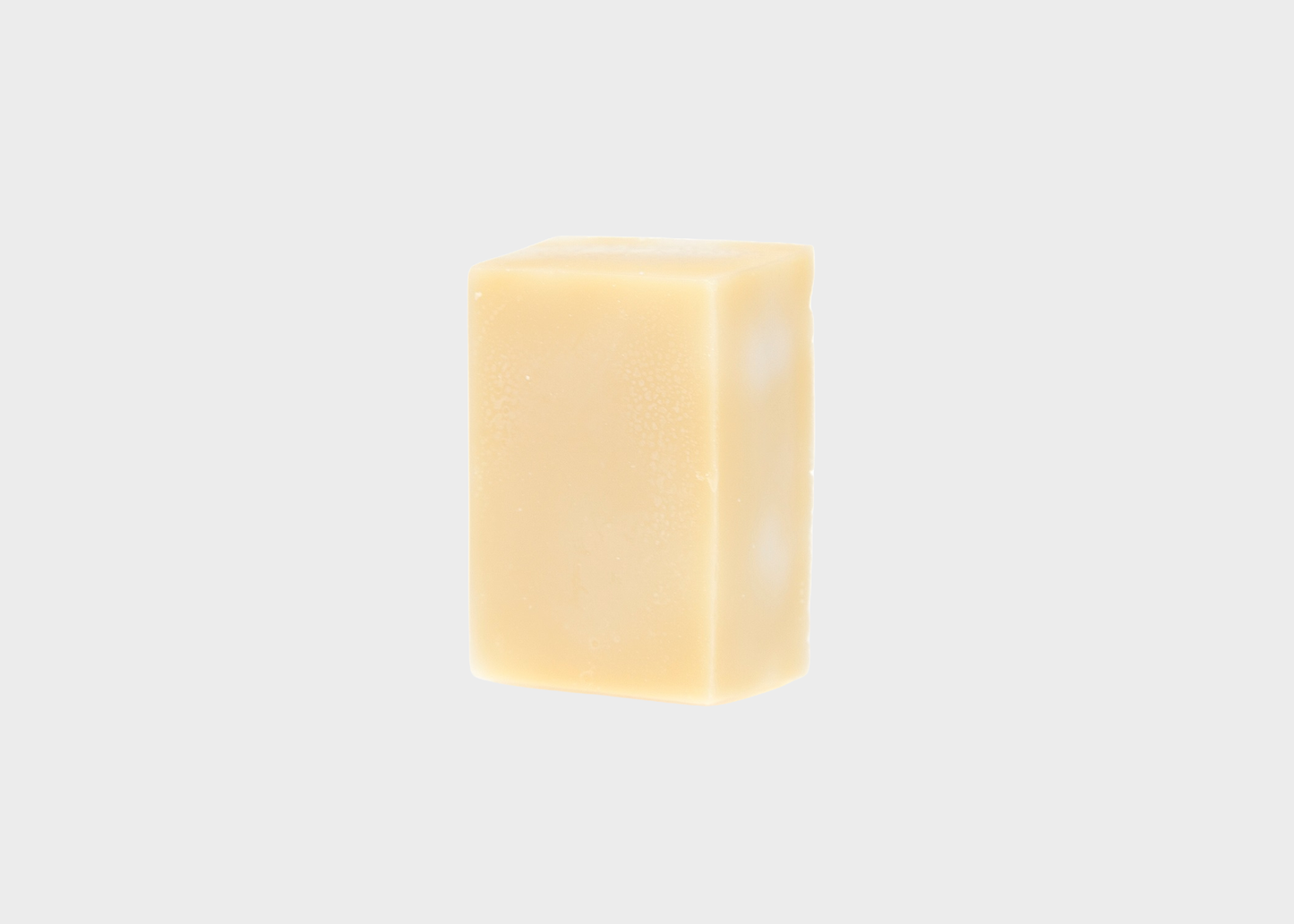 
                  
                    A single rectangular bar of pale yellow soap or shampoo centered on a light gray background.
                  
                