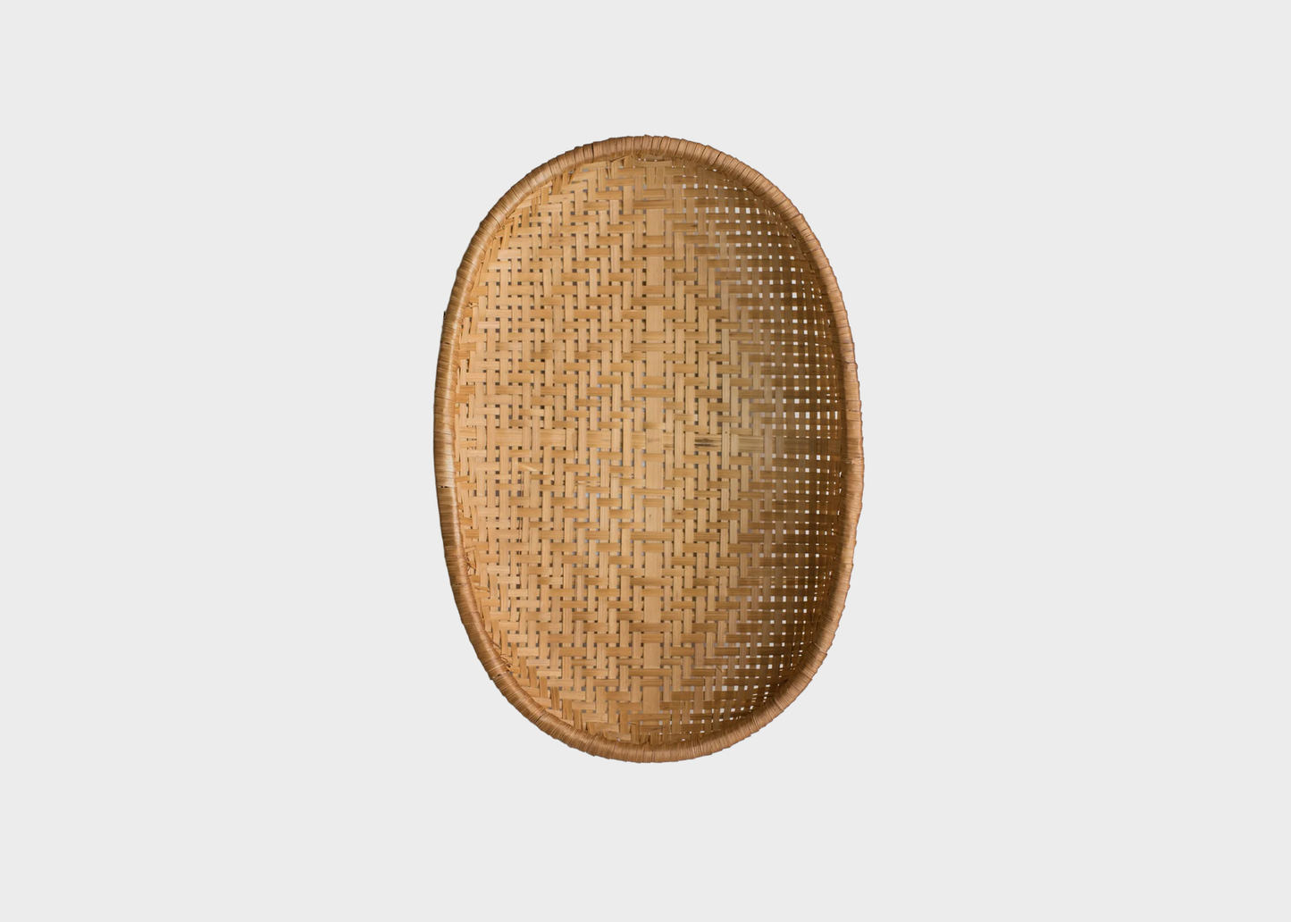 
                  
                    An oval woven rattan tray with a natural light brown color, shown from a top-down view on a solid light gray background.
                  
                