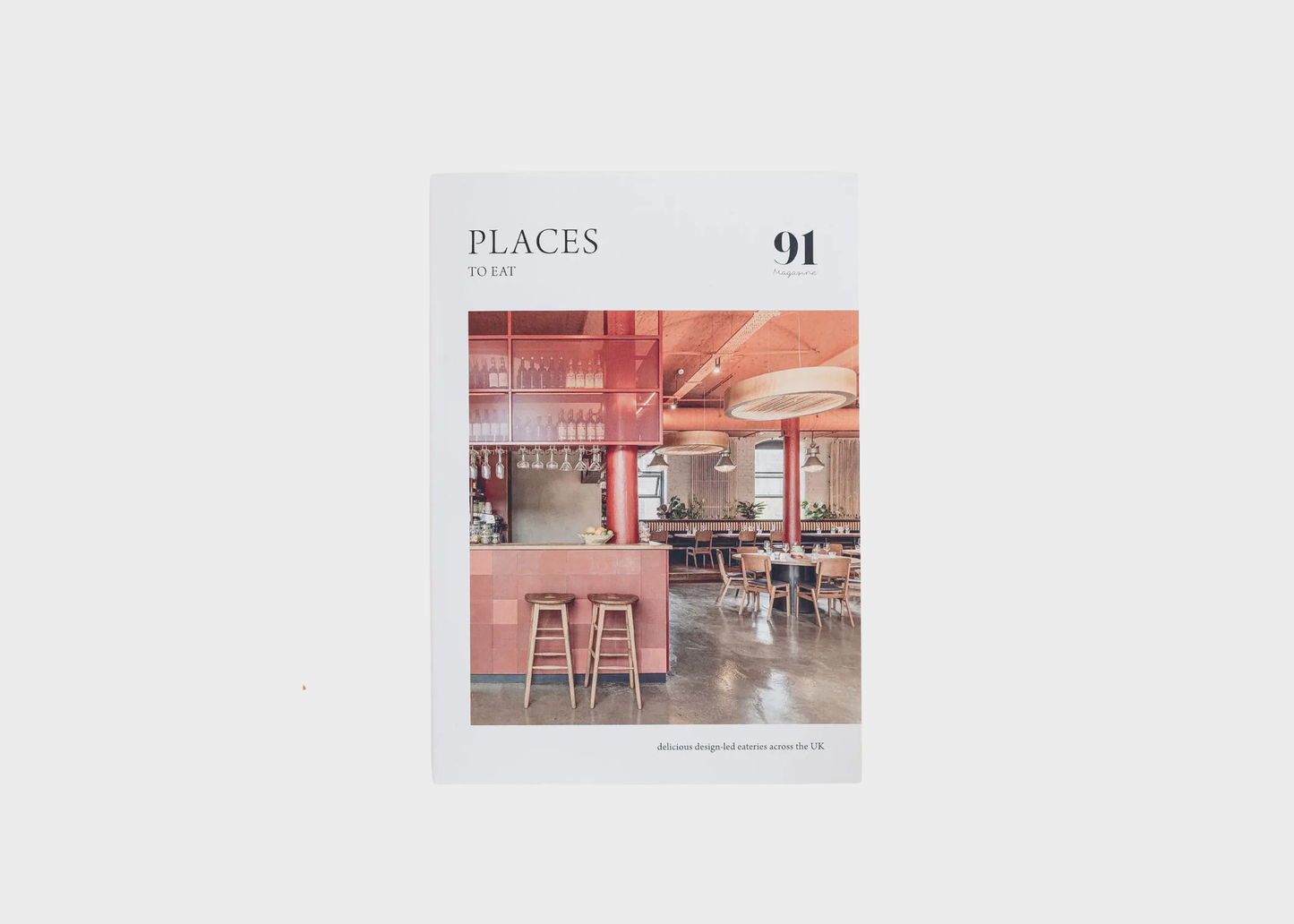 
                  
                    A book titled 'PLACES BY ART 91' centered on a light gray background. The cover features a photograph of a modern interior space with warm red, pink, and brown tones, plus the text 'delicious design led eateries across the UK'.
                  
                