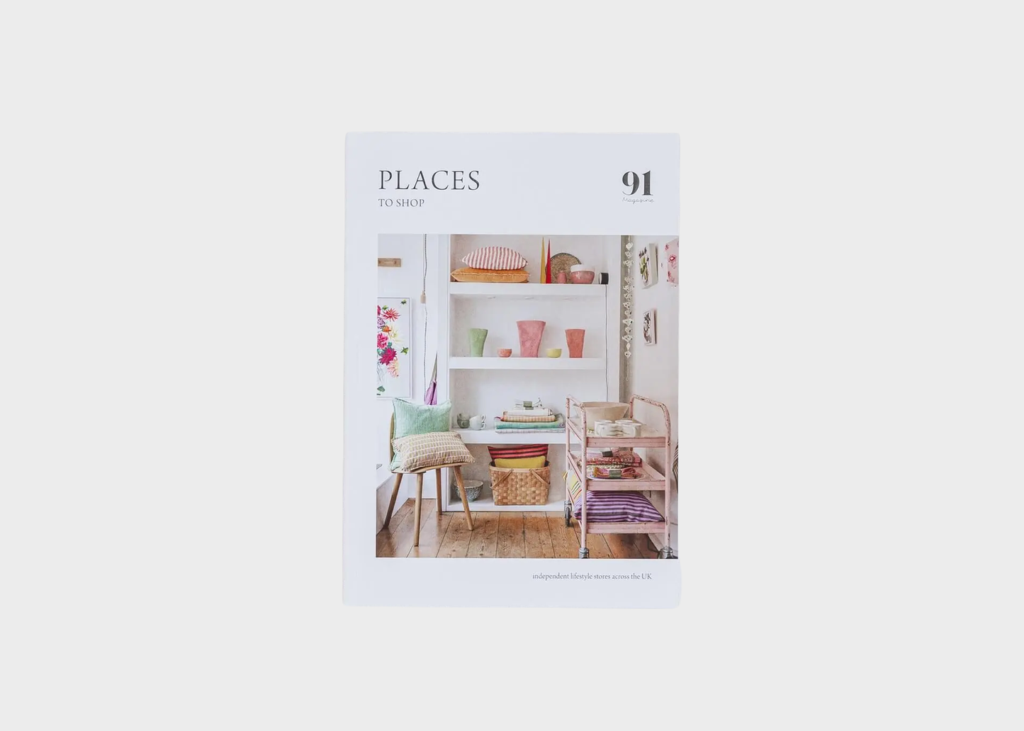 
                  
                    A book or magazine cover titled 'PLACES TO SHOP' with the number 91, featuring a photograph of a cozy, pastel-colored room with shelves, a chair, and a rolling cart, centered on a light gray background.
                  
                