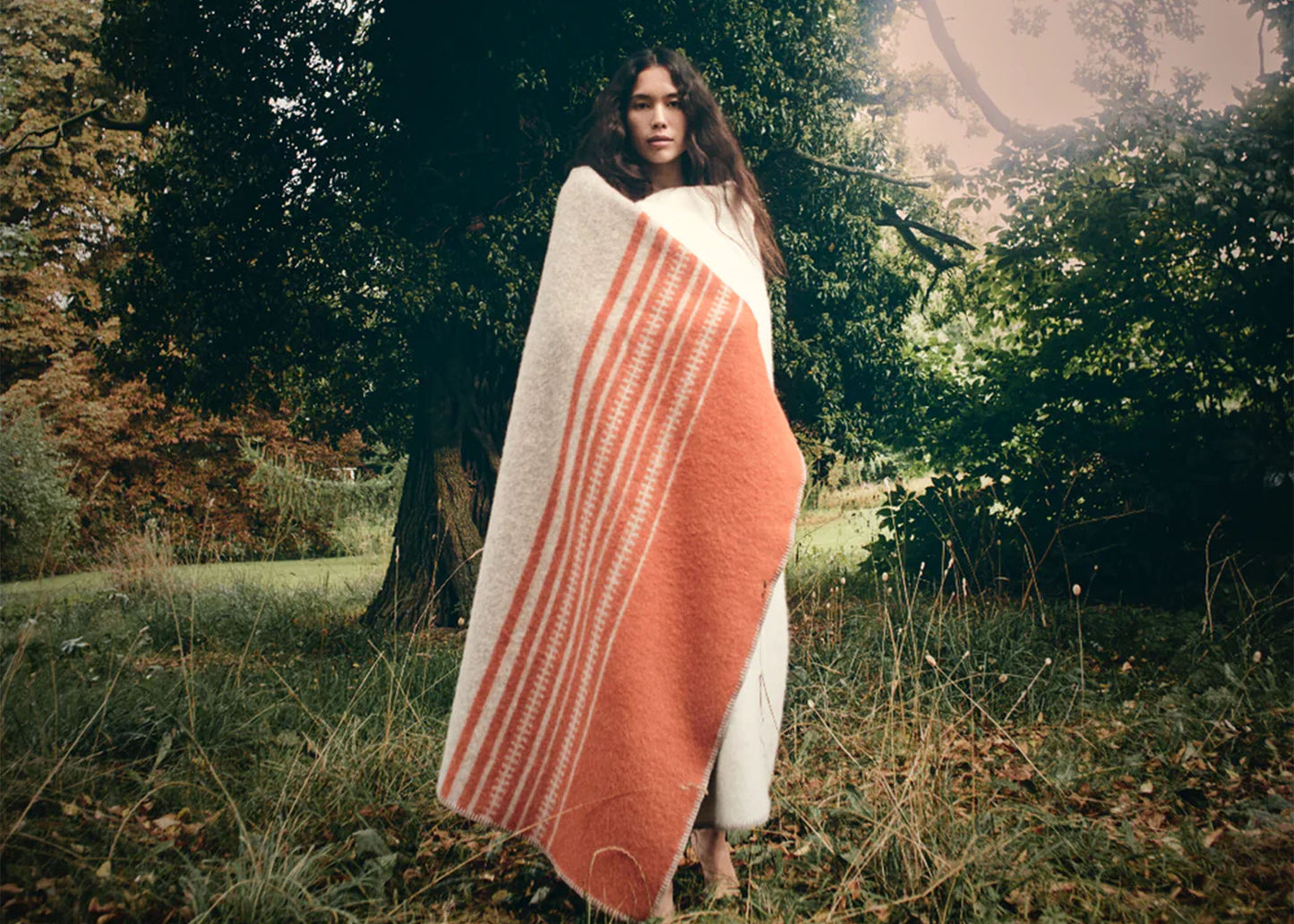 
                  
                    Aiyana no. 01 - Creme/Orange Blanket by Hein Studio wrapped around a model in nature
                  
                