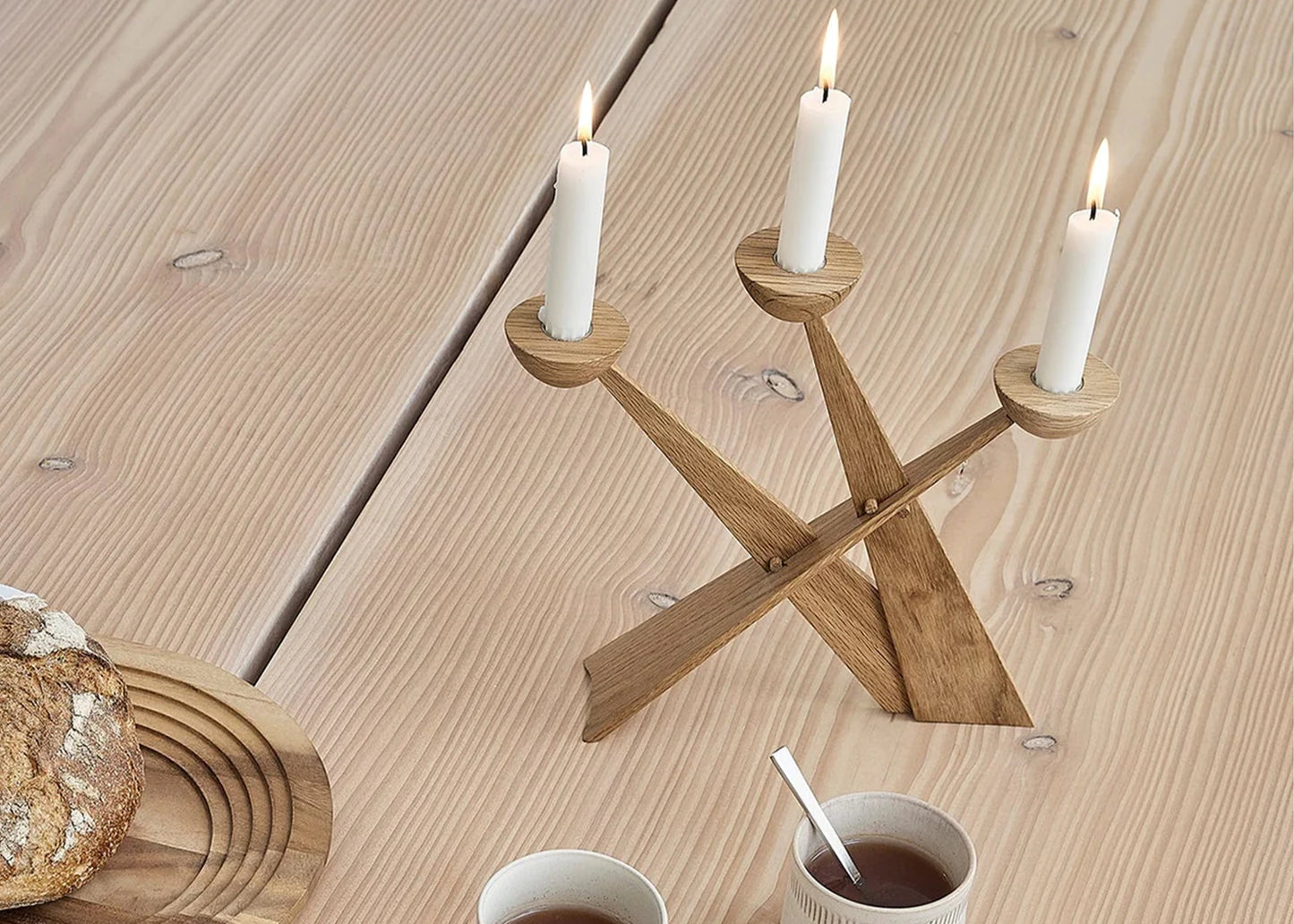 Caravel Oak Candlestick Holder with lit candles on a wooden table surrounded by bread and coffee