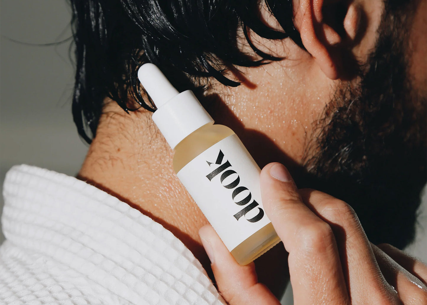 
                  
                    Conditioning Hair Oil by DOOK held up by hand against a wet neck
                  
                