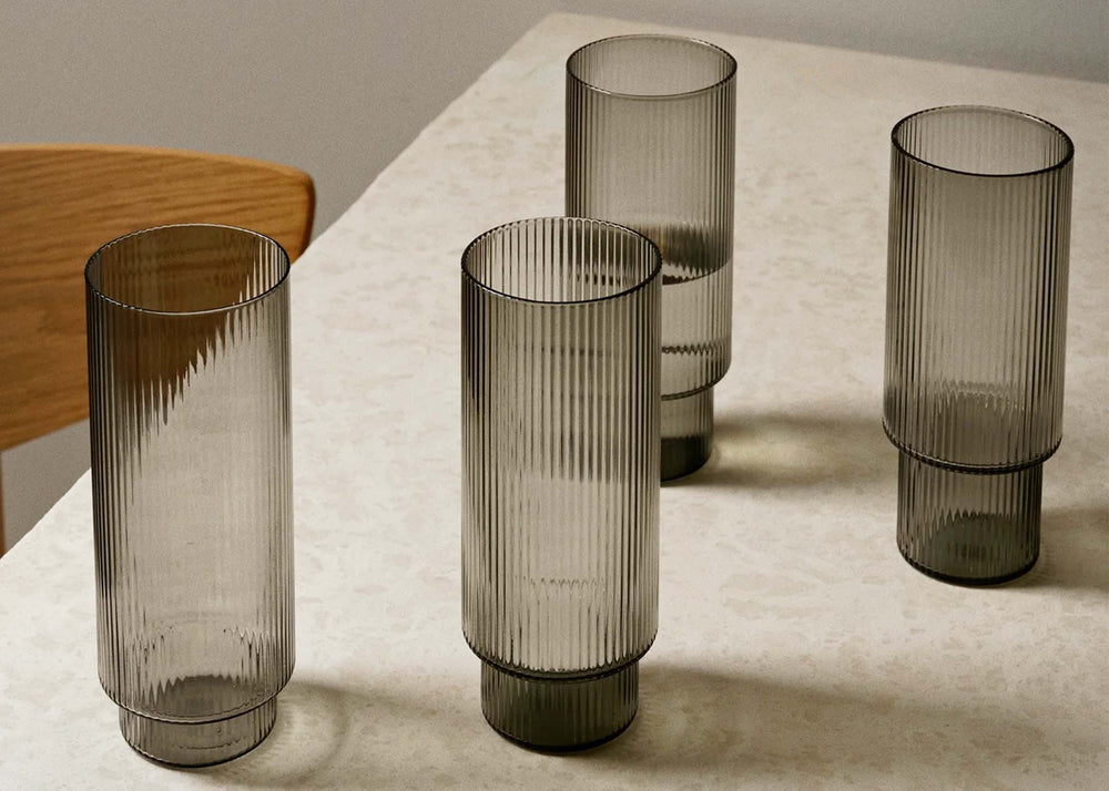 
                  
                    Grey Ripple Long Glasses by Ferm Living on a dining room table
                  
                