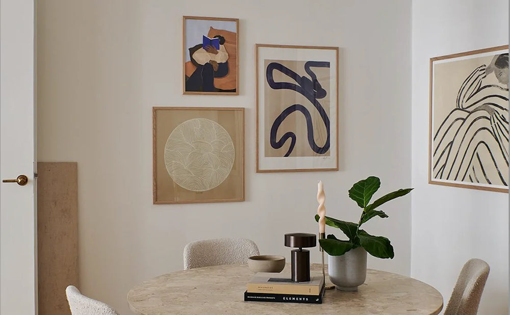 Midcentury modern prints on a home wall next to a dining table