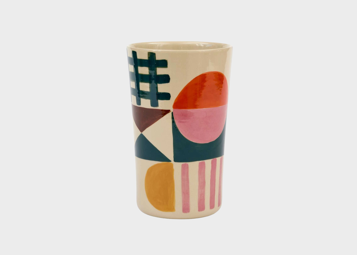 
                  
                    A cylindrical ceramic vase with a cream-colored base decorated with a colorful geometric pattern of circles, squares, and stripes in pink, orange, yellow, and dark green.
                  
                