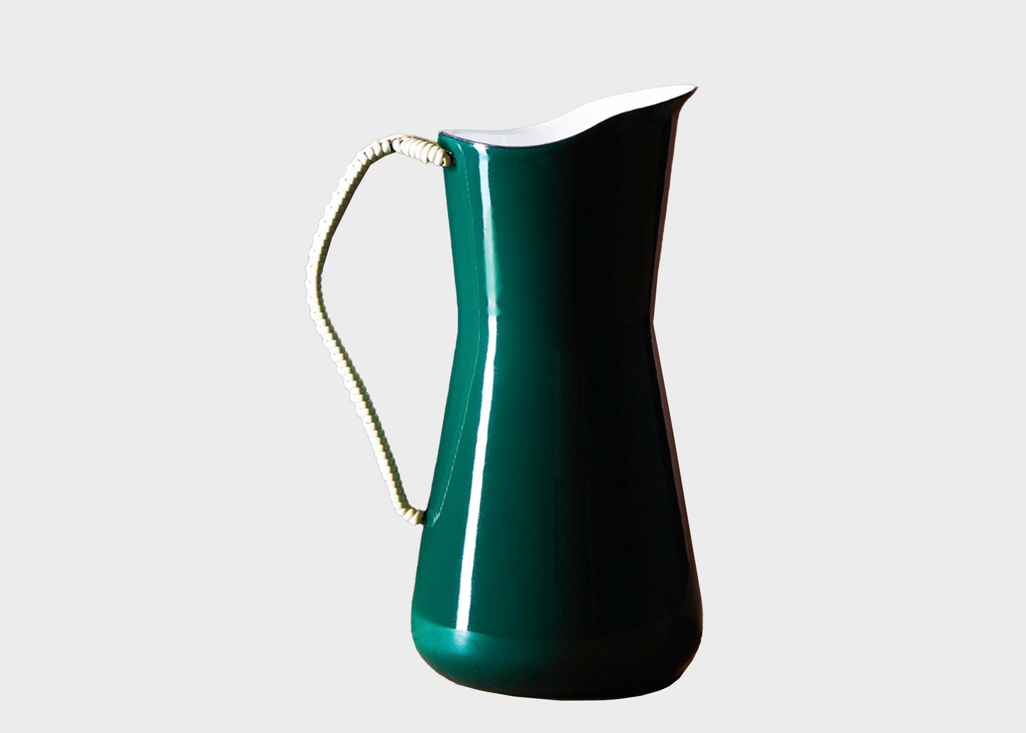 Green pitcher with a woven handle on a light gray background