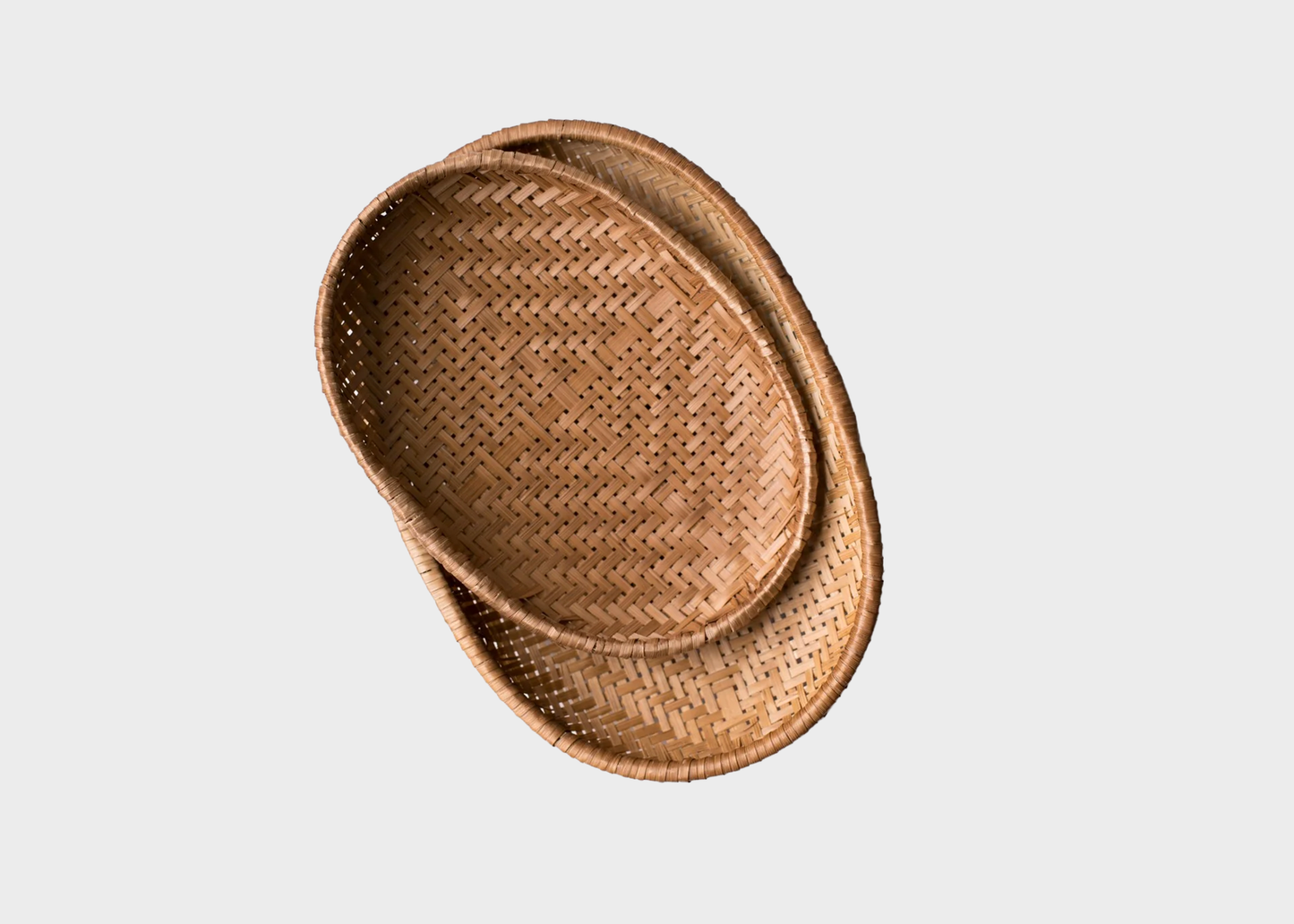 
                  
                    Two nested oval woven rattan baskets with a natural brown color, shown from a top-down perspective on a light gray background.
                  
                