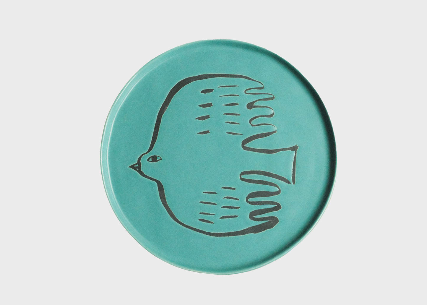 Turquoise ceramic plate with a bird design on a light gray background