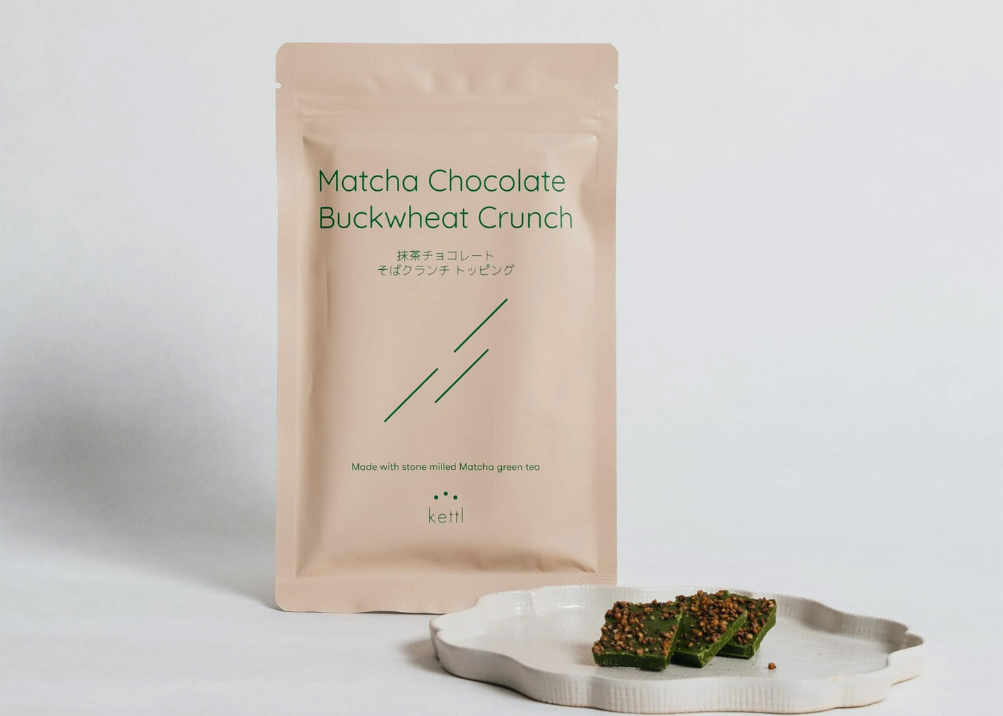 
                  
                    Matcha Chocolate Buckwheat Crunch packaging with a small plate of snacks on a light background
                  
                