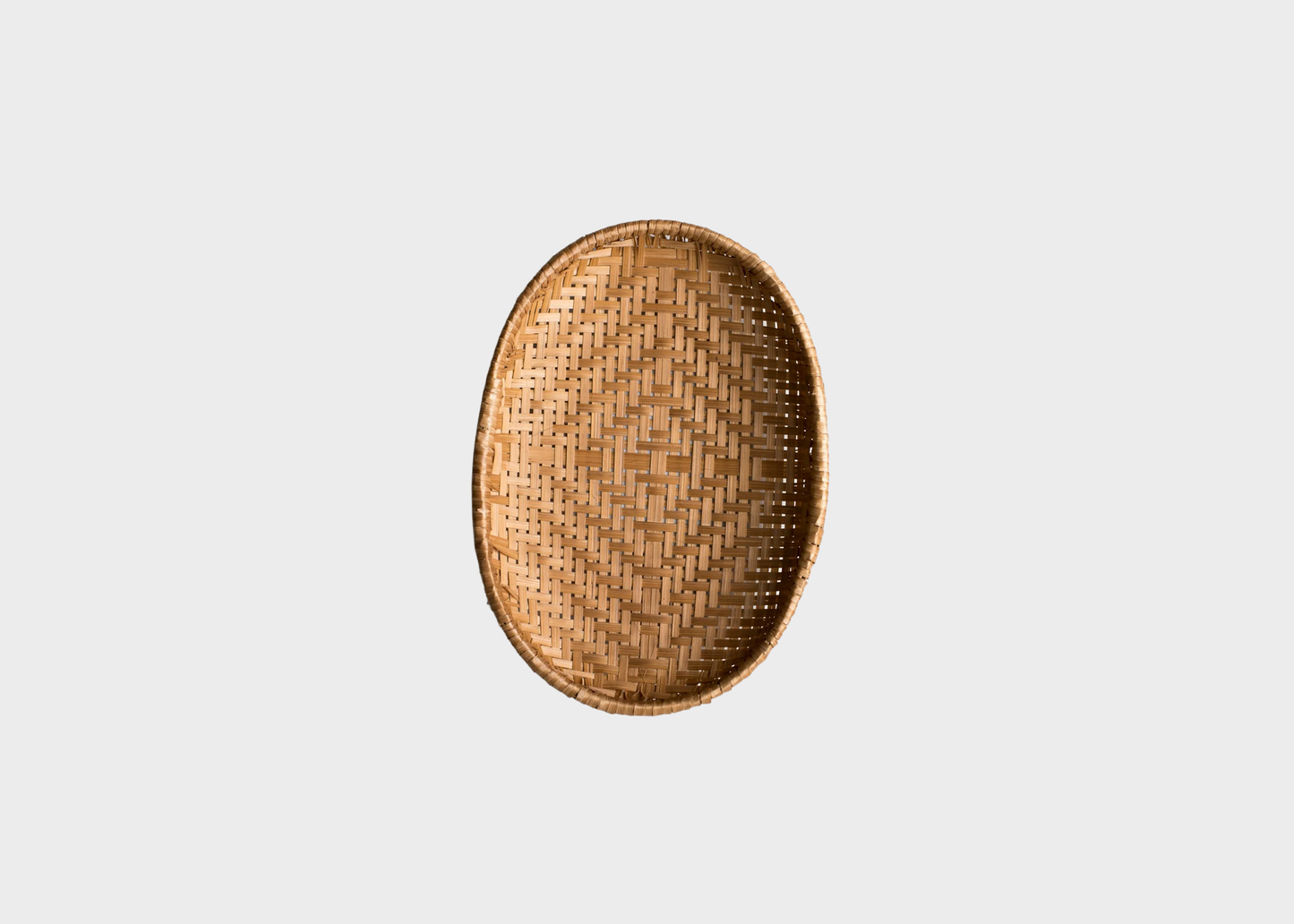 
                  
                    An oval woven bamboo tray with a natural light brown color, shown from a top-down view against a solid light gray background.
                  
                