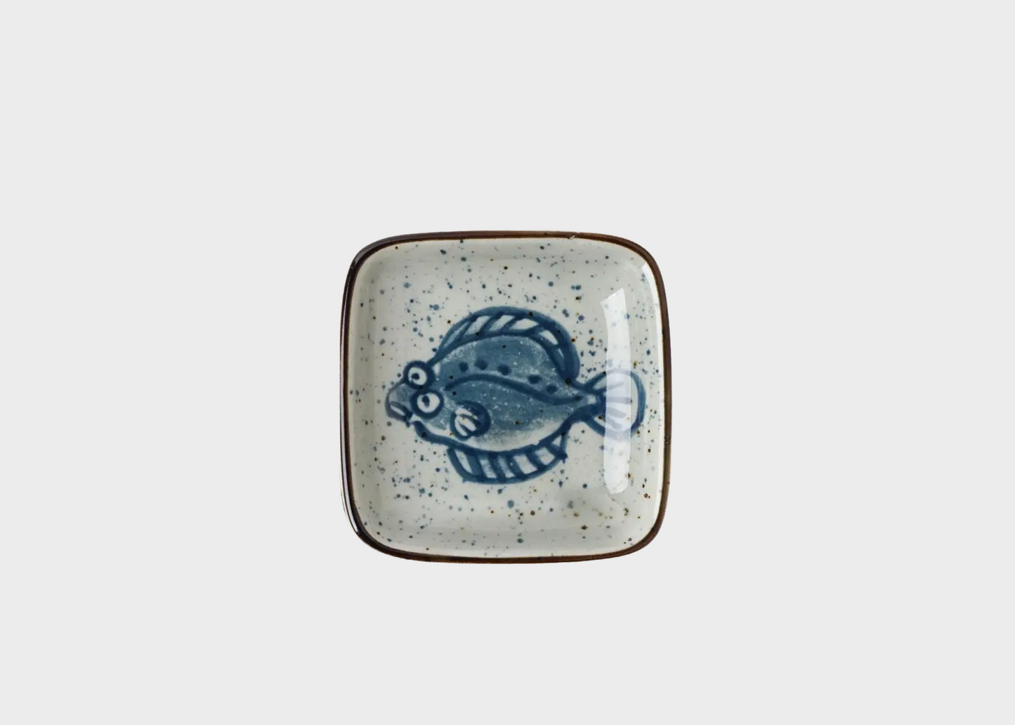 Ceramic dish with a fish design on a light gray background