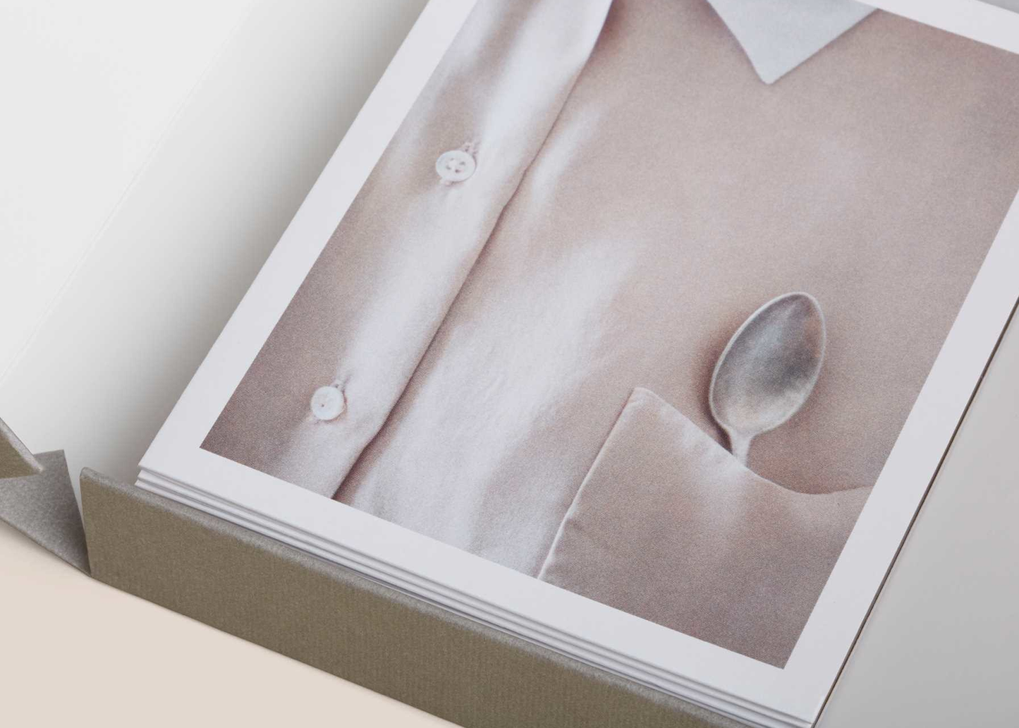 Close-up of a photo album with a photograph of a shirt and spoon on a plain background