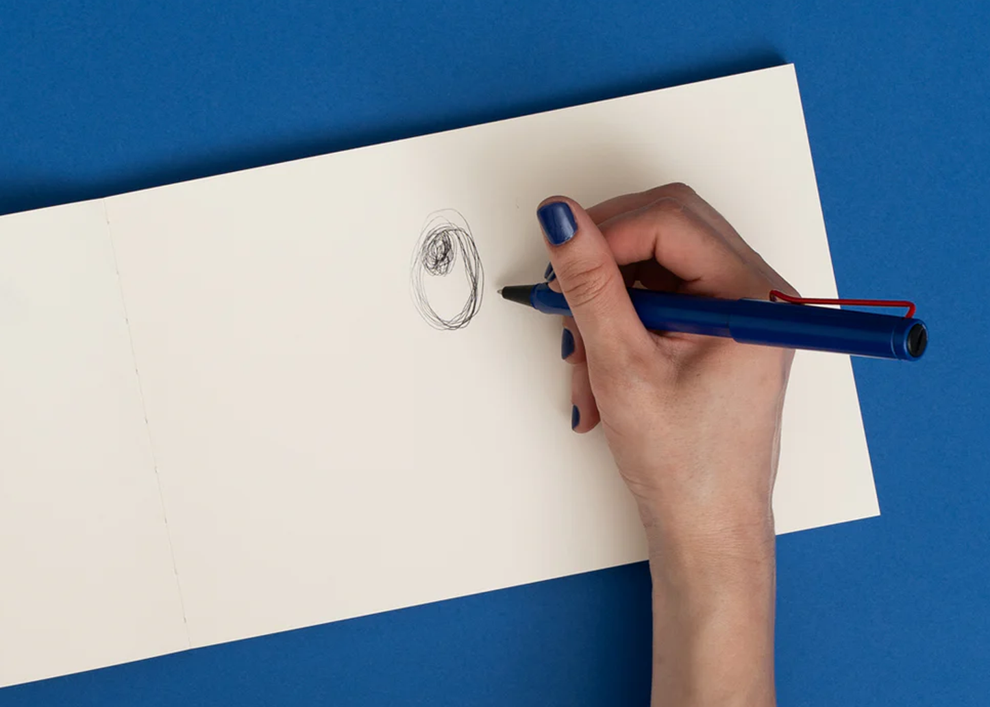
                  
                    woman drawing an eye inside of a sketchbook with a pen
                  
                