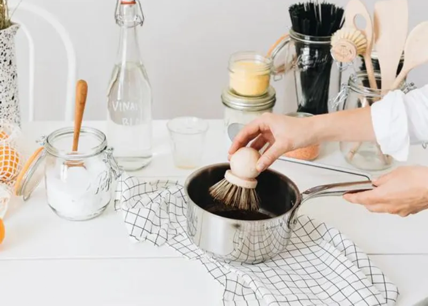 
                  
                    Person cleaning a pot with a brush on a kitchen counter.
                  
                