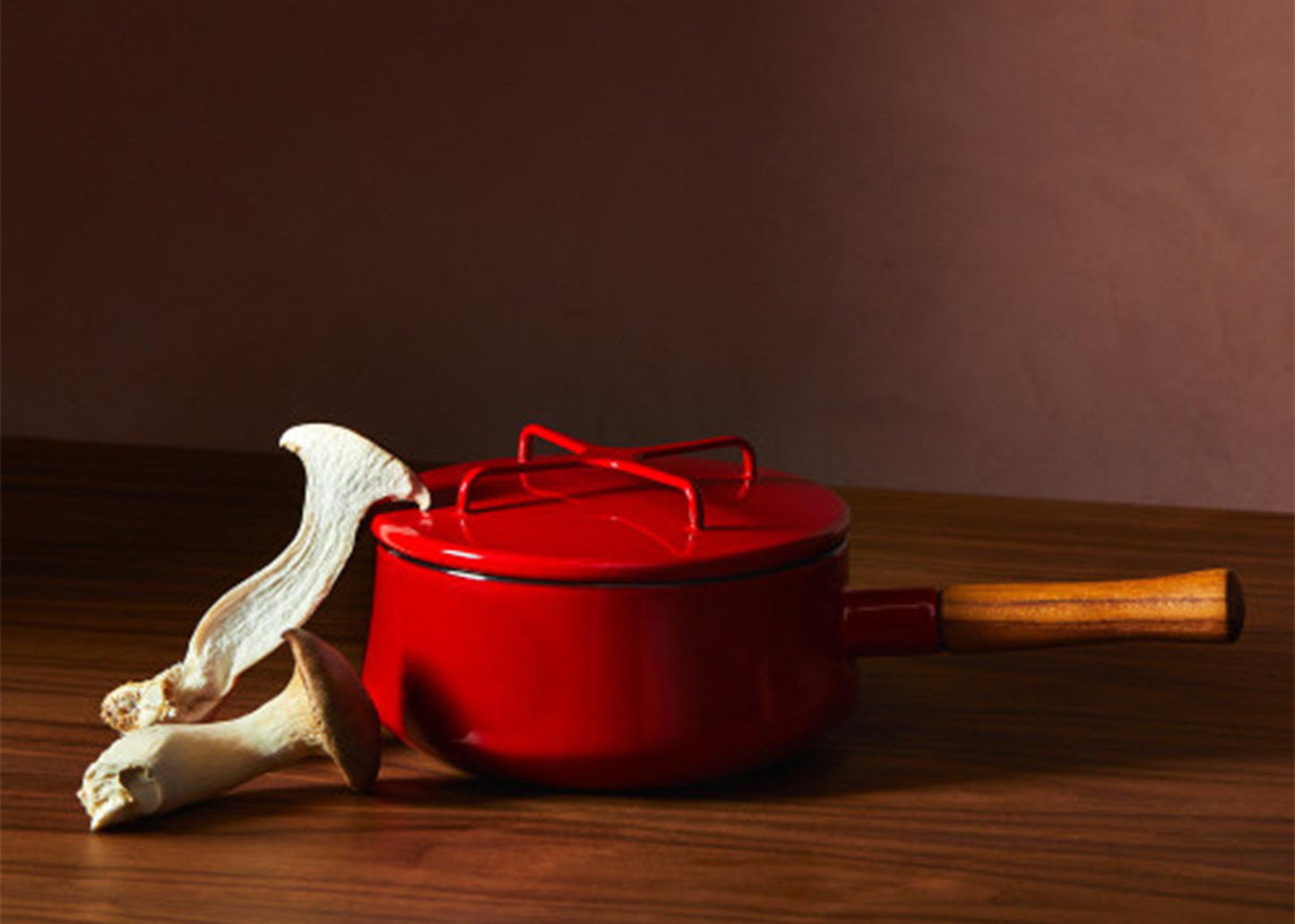 
                  
                    Red enamel Dansk pot with a wooden handle on a wooden surface
                  
                