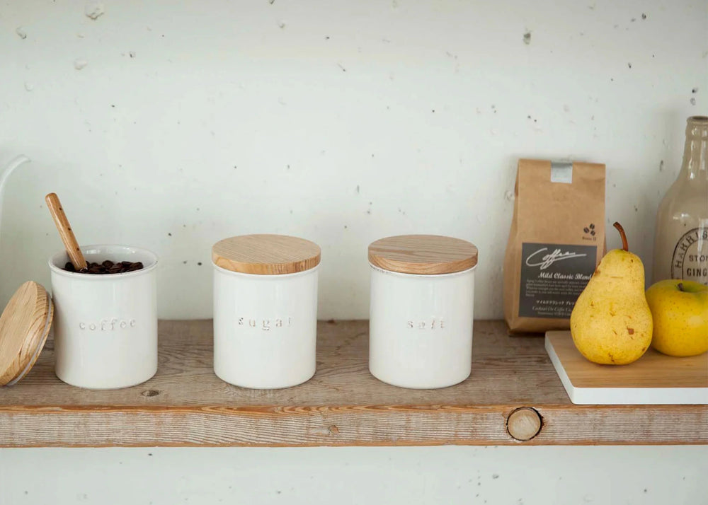 Ceramic Salt Canister by Yamazaki with a white ceramic base and a wooden lid on a counter top