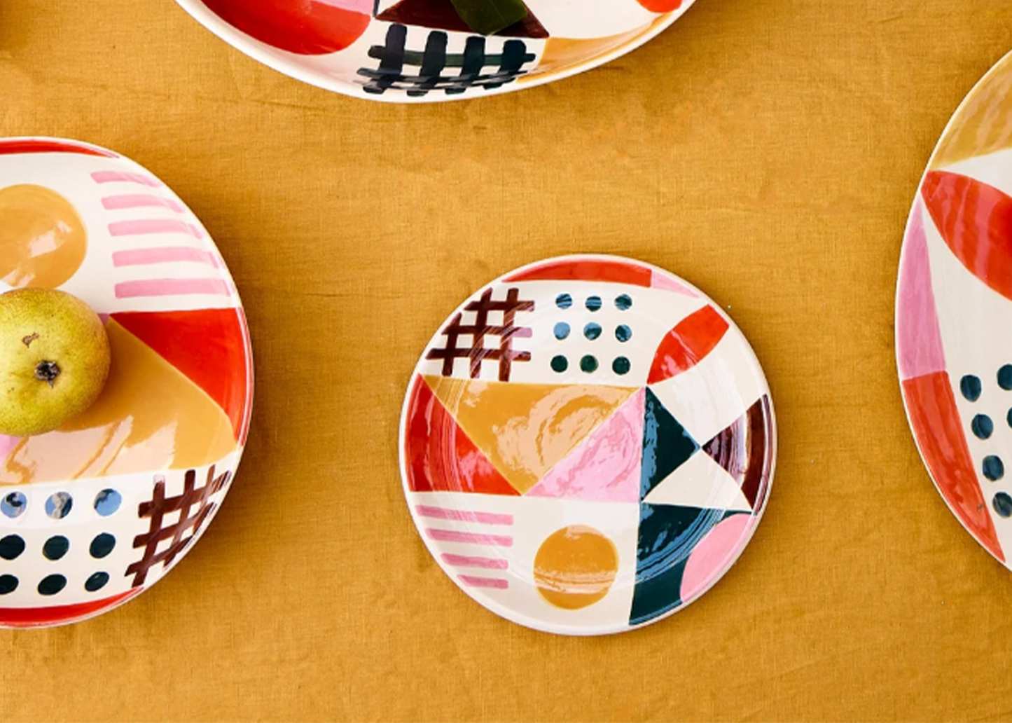 Colorful ceramic plates with geometric patterns on a yellow surface