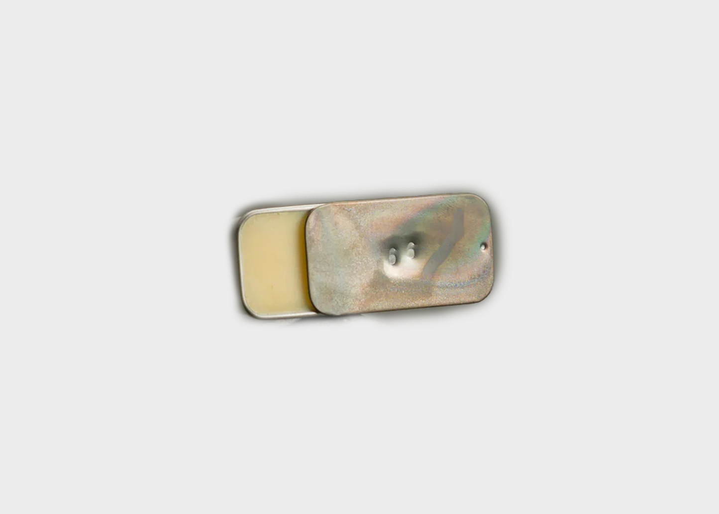 Metallic container filled with Fischersund's Utilykt solid perfume on a light gray background
