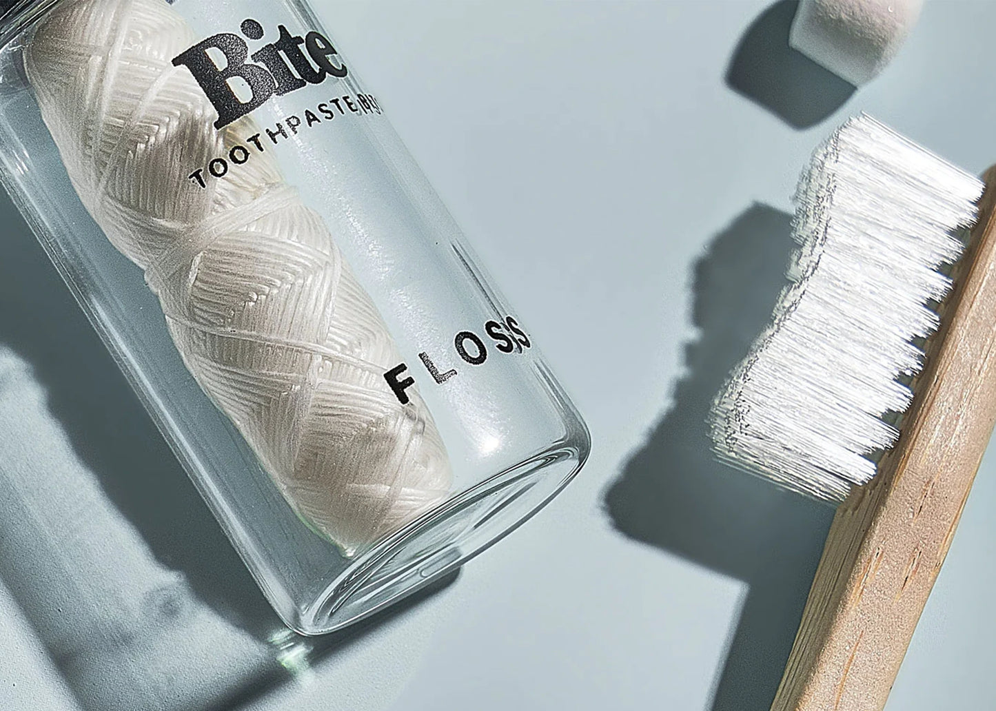 Bite Floss in a glass jar next to a toothbrush sold at Woodland Mod