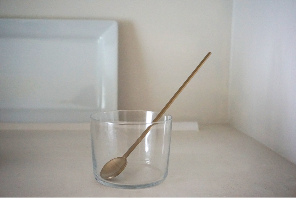
                  
                    A brass Fein Long Spoon by Ferm Living in a glass cup
                  
                