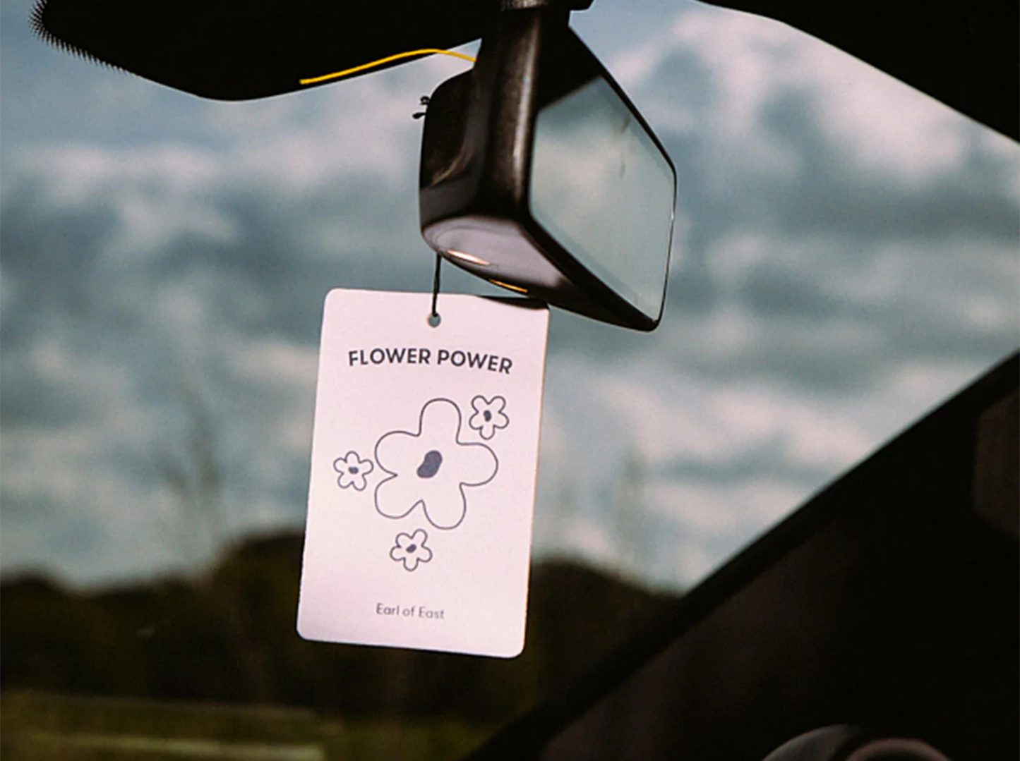 Flower Power Air Freshener by Earl of East hanging inside of a car window.