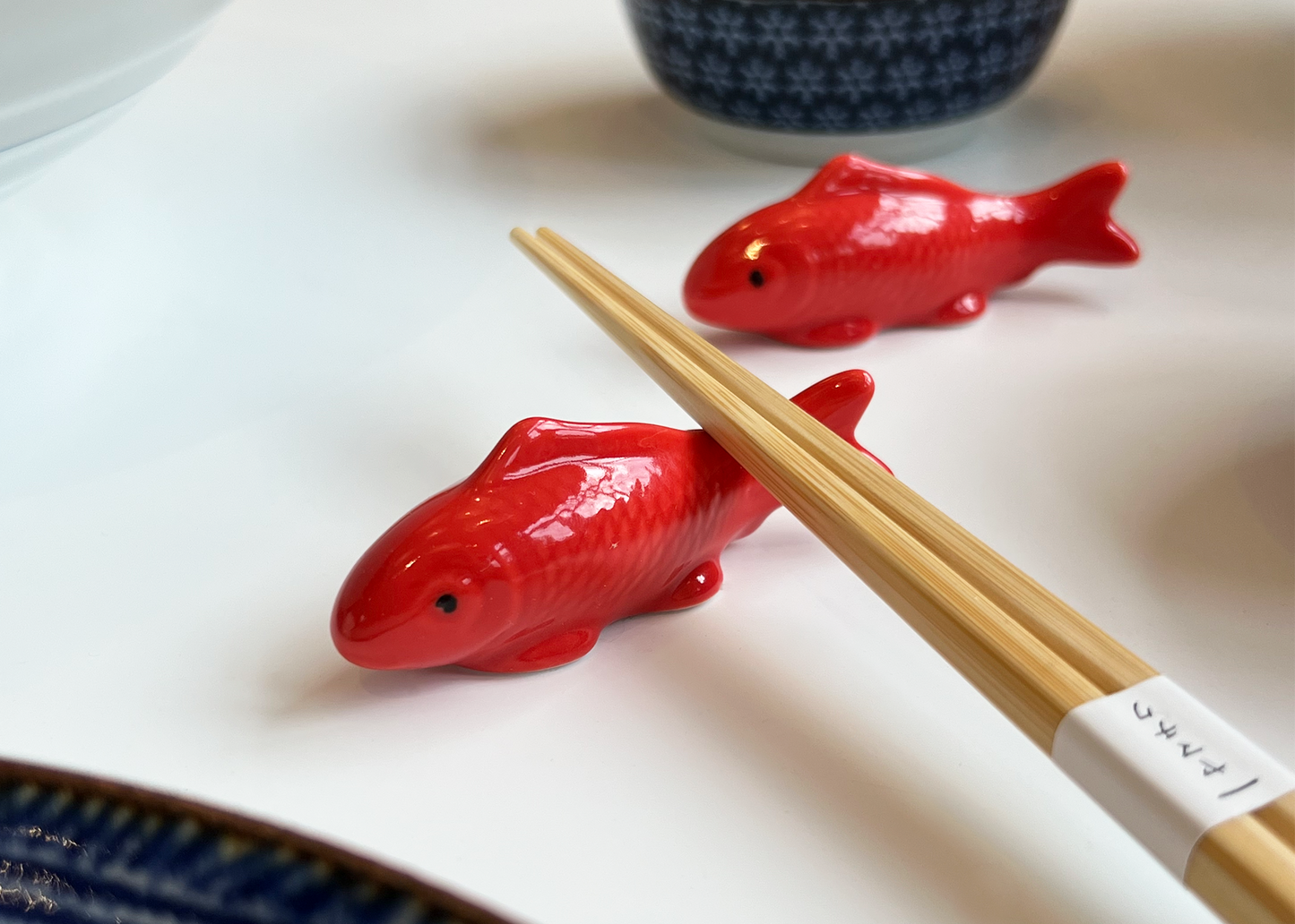 Chopsticks resting on the bright red ceramic koi fish chopstick rest as sold by Woodland Mod