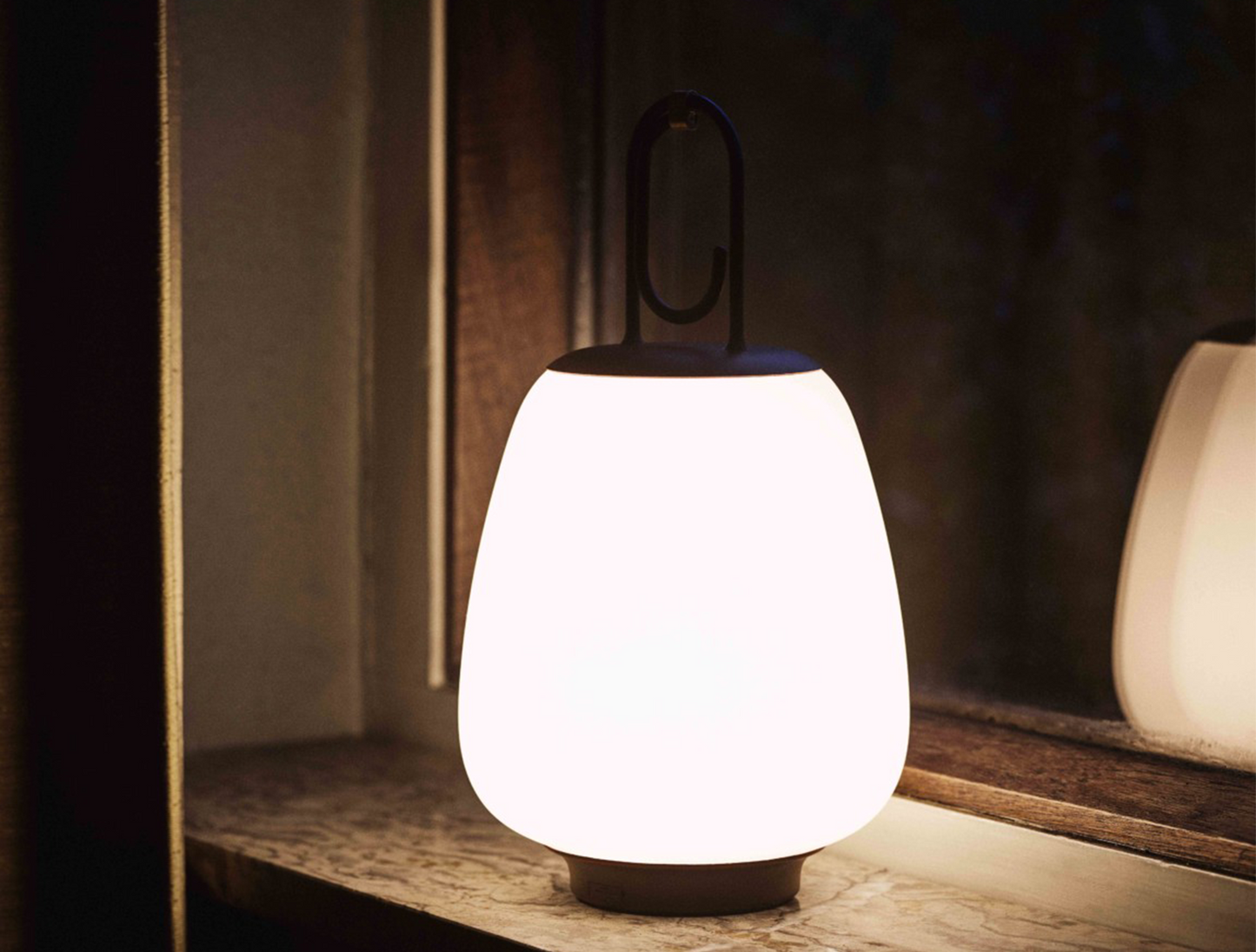 An illuminated Lucca Lamp SC51 in a dark room against the backdrop of a mirror