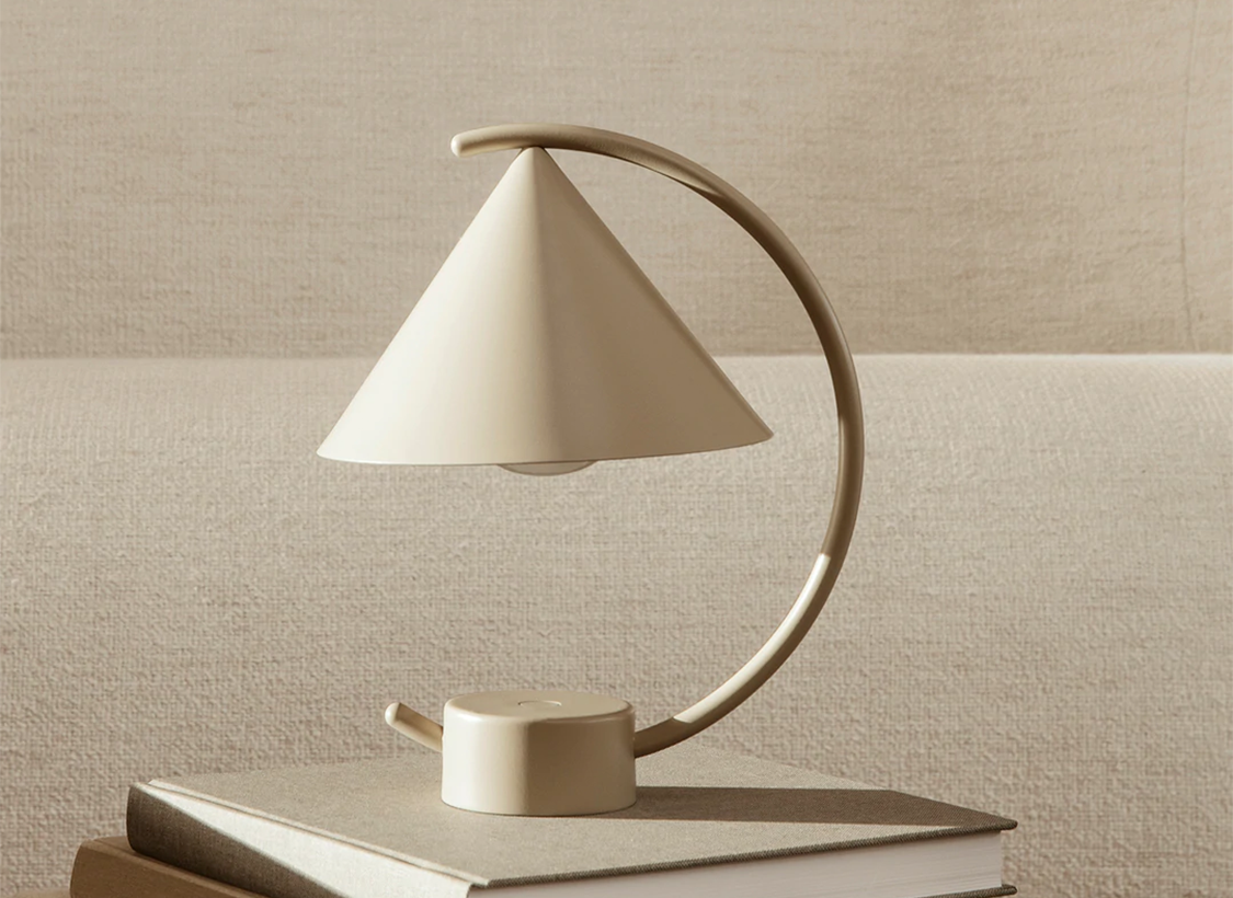 The cashmere Meridian Lamp by Ferm Living resting on a book in a living room as sold by Woodland Mod