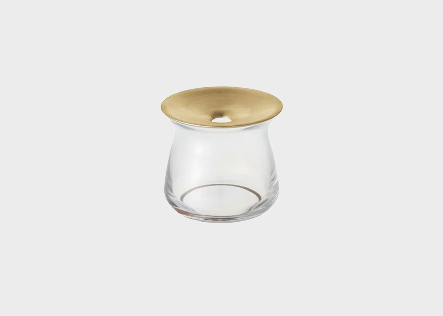 A small LUNA vase made of glass with a gold brass lid and a hole for inserting flowers.