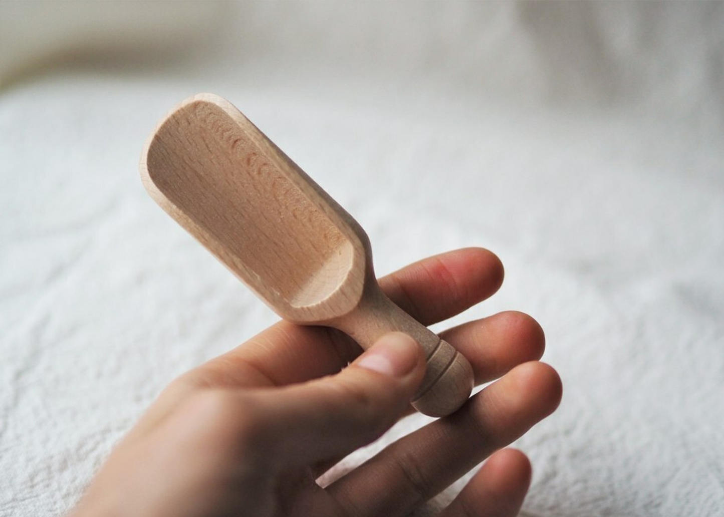 
                  
                    A small wooden tea scoop being held by a hand for scale.
                  
                