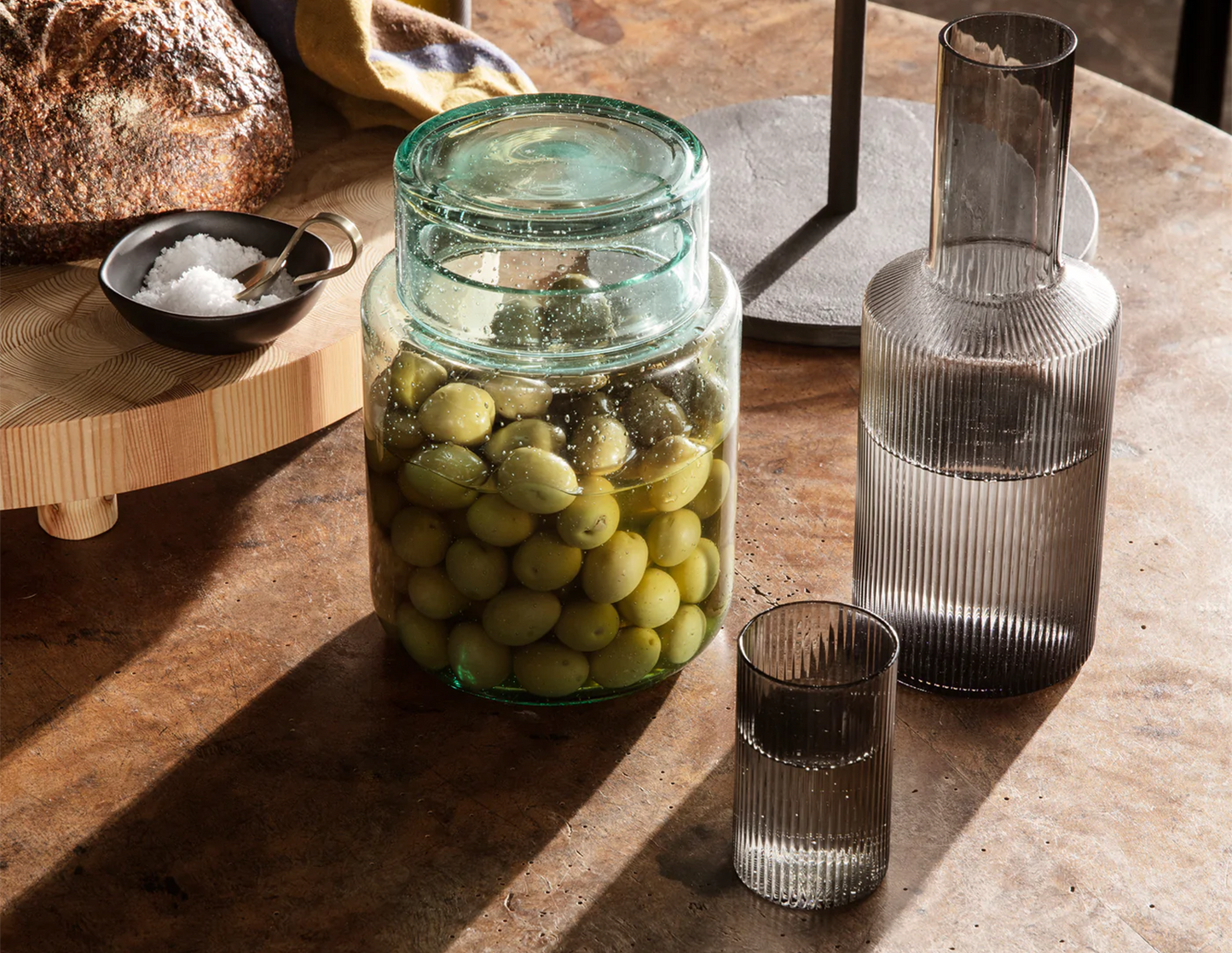 Grey Smoked Ripple Verrines by Ferm Living on a table setting next to olives and a carafe
