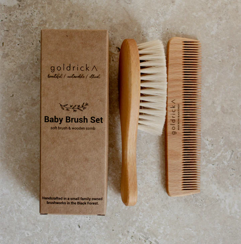 
                  
                    A wooden hairbrush and comb intended for toddlers and babies by goldrick next to packaging box
                  
                