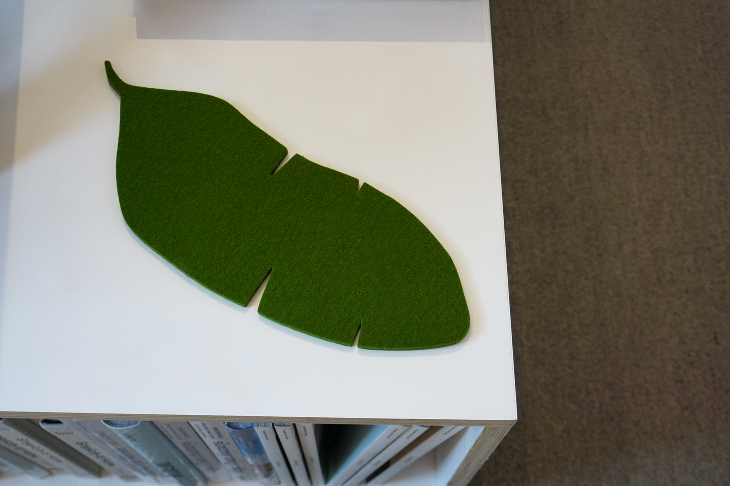 A felt trivet shaped as a banana leaf on a counter at Woodland Mod