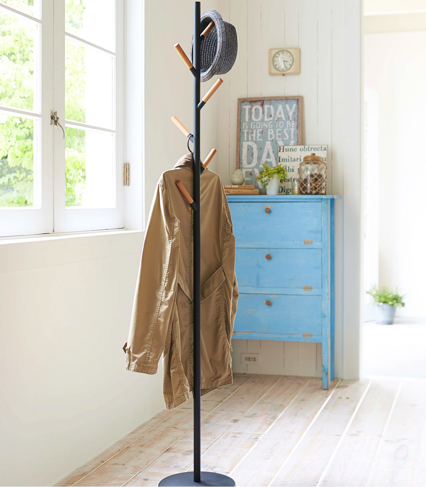
                  
                    Wood Branch Steel Coat Rack in Black by Yamazaki with coats and hats resting on the pegs
                  
                