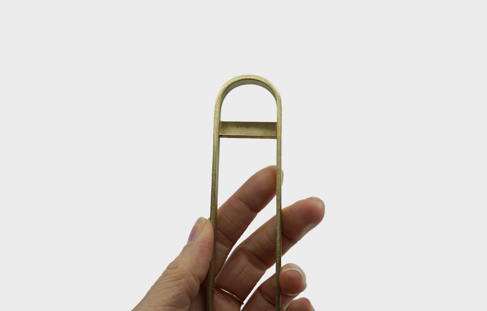 
                  
                    Brass Bottle Opener by Ferm Living held by a hand
                  
                