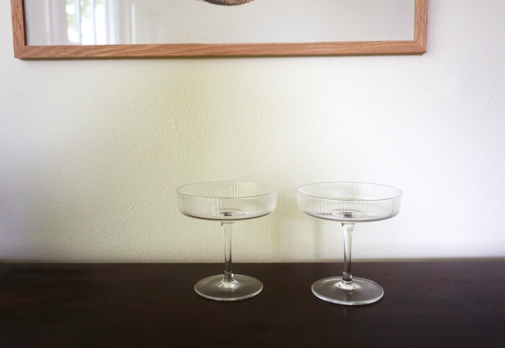 
                  
                    Clear ripple champagne glasses by Ferm Living on a table top setting
                  
                