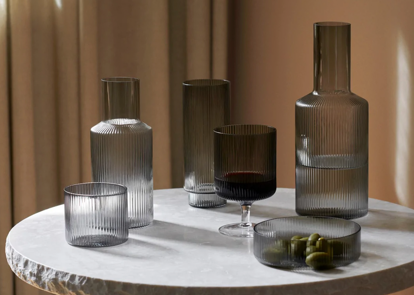 Grey Smoked Ripple Wine Glasses by Ferm Living next to other ripple series glassware