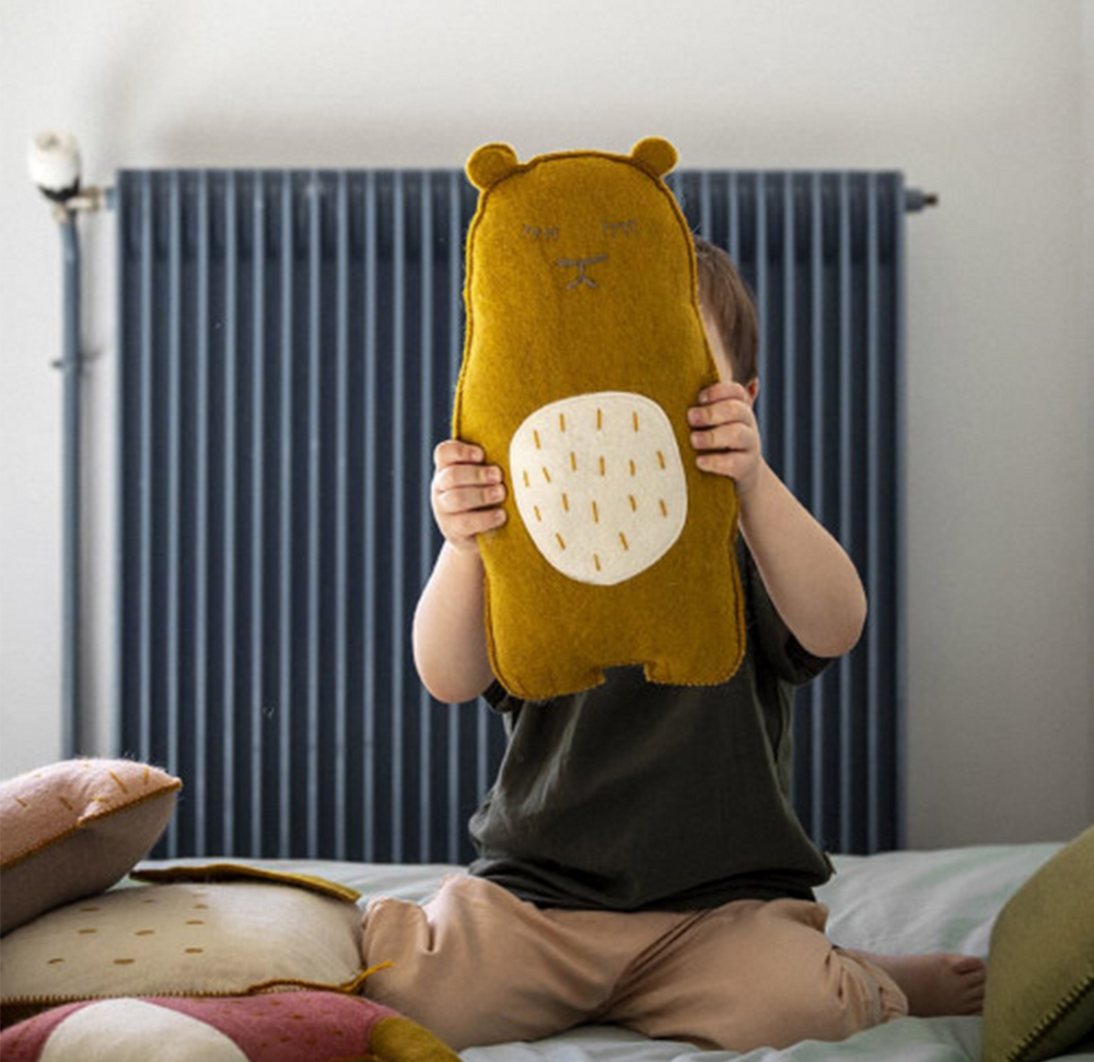 
                  
                    A child holding a gold teddy bear with a white stomach on the bed
                  
                