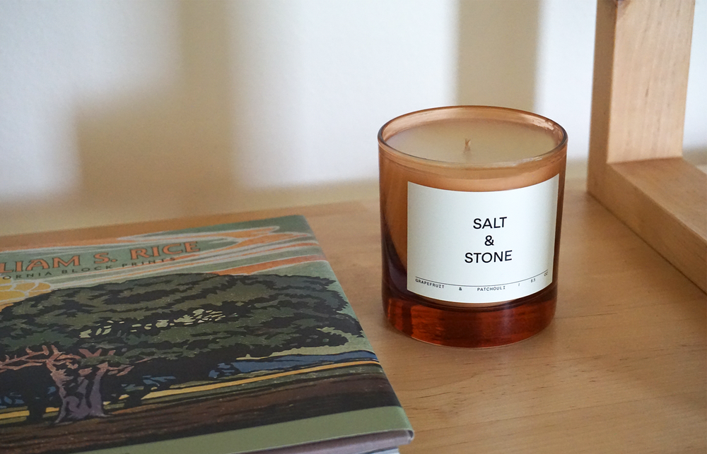 
                  
                    Grapefruit & Patchouli Candle by Salt and Stone with pink glass on a shelf
                  
                